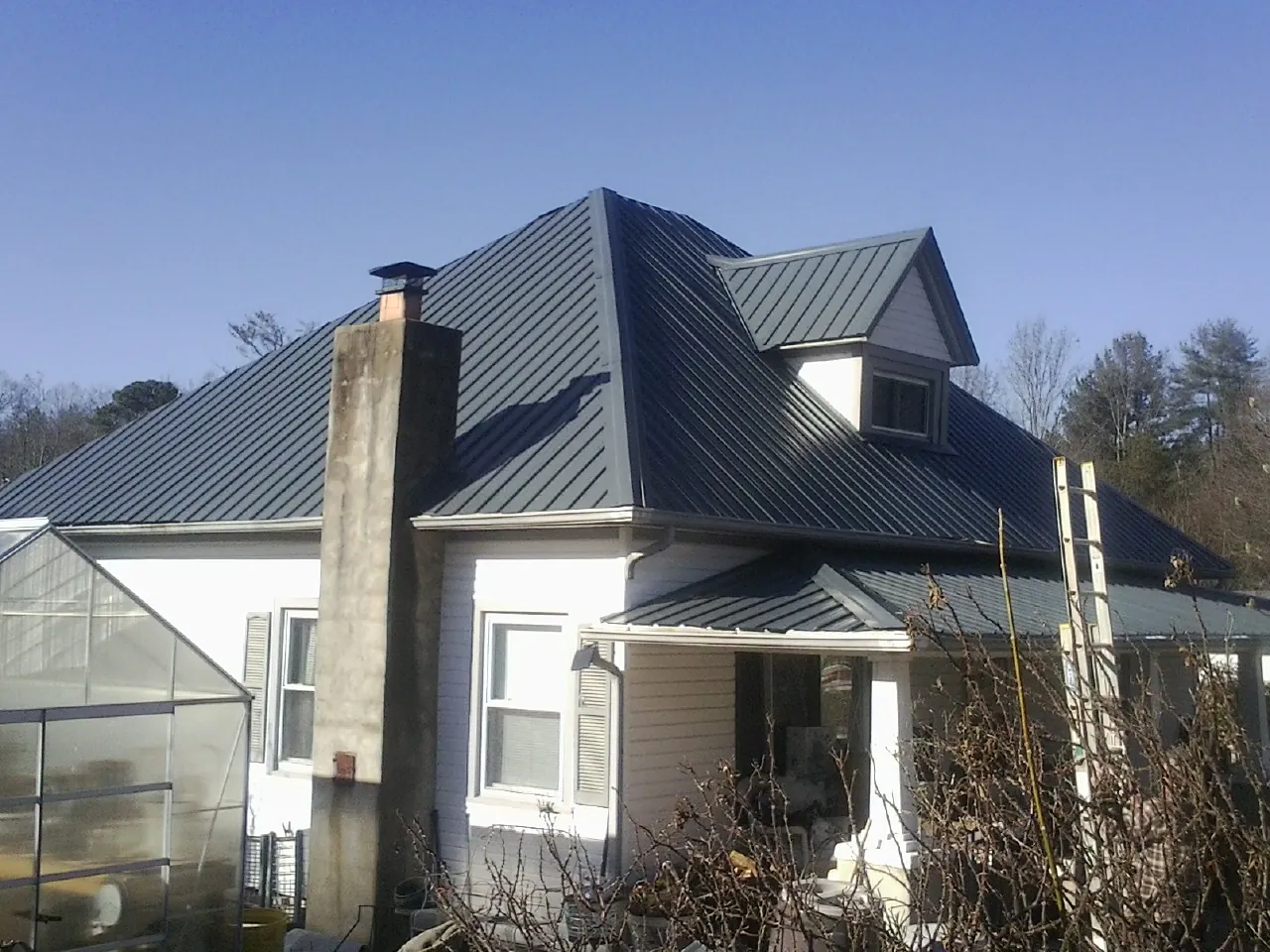 Dark blue standing seam metal roof on a white farmhouse with dormer — Slate & Tile Roof Repair by Roofing Brothers in Tow