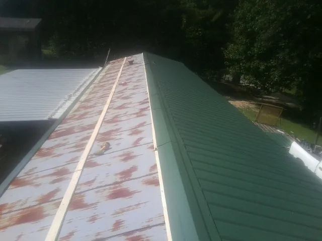 Old rusted panels beside newly installed green metal roofing — Wind Damage Roof Repair by Roofing Brothers in Tow