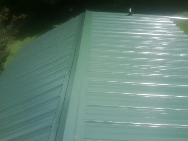New green metal panels meeting at the ridge of a roof — Flat Roof Repair work by our crew in Tow