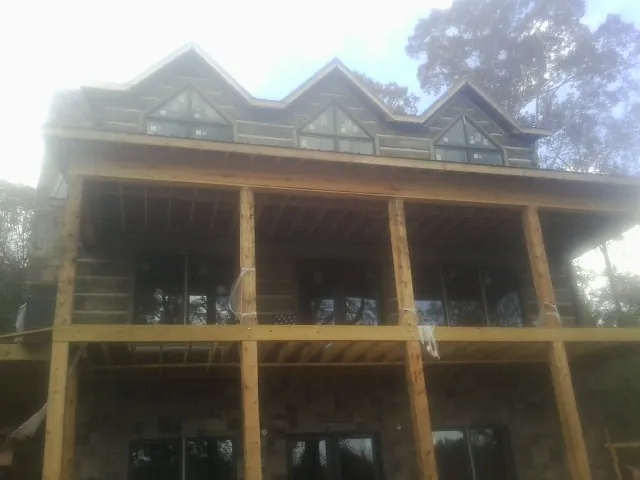 Dormers and porch framing on a large log home under construction — Roof Coating work by our crew in Tow