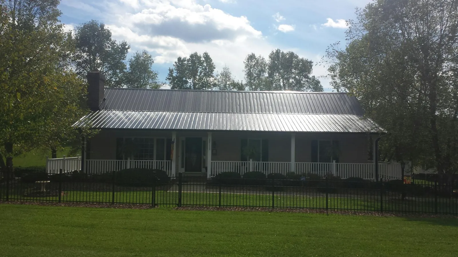 Gray metal roof on a brick ranch with a full width front porch — Gutter Guard Installation work by our crew in Tow