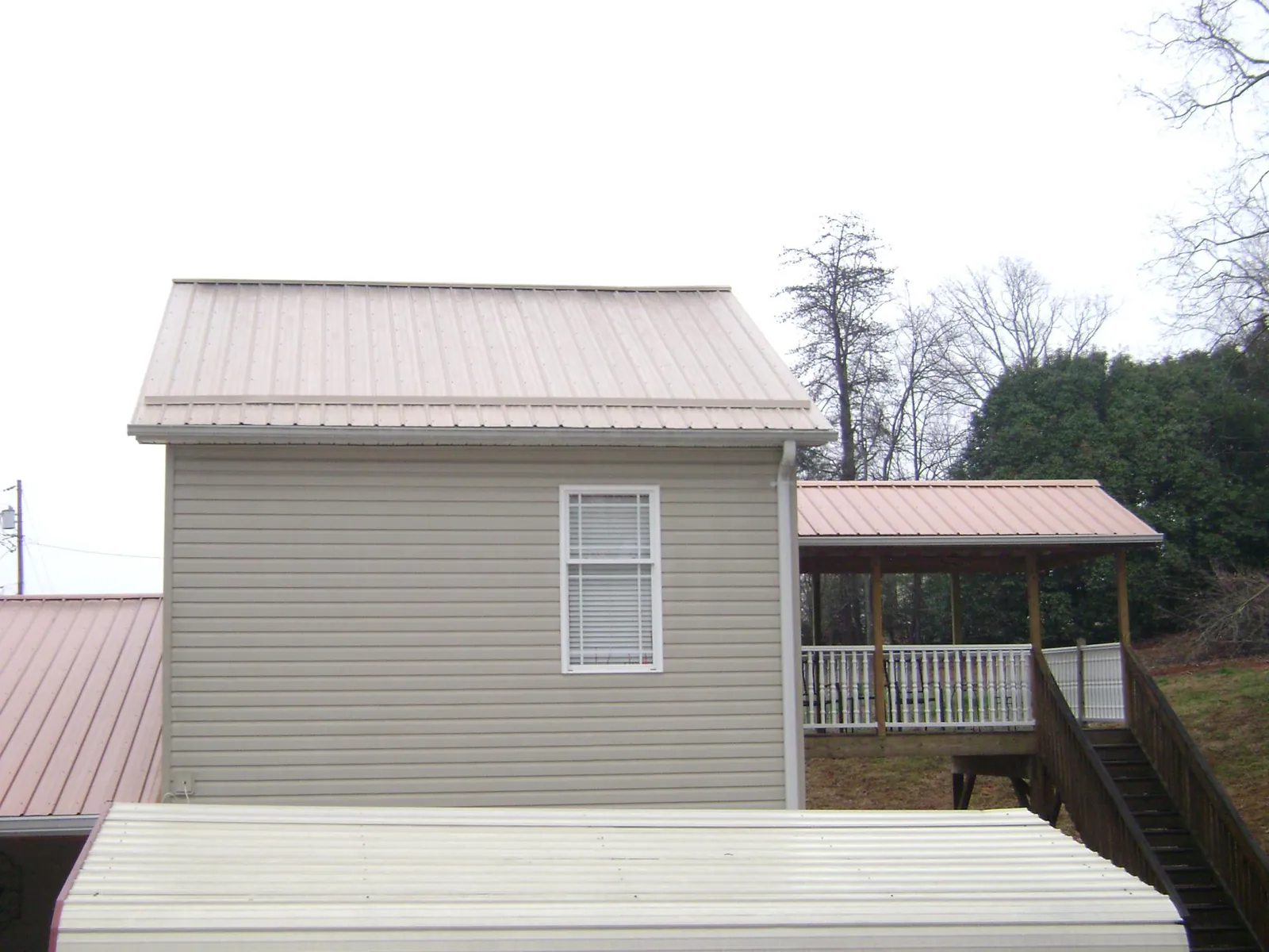 Tan metal roofs on a two story addition and attached porch, from a Roof Replacement job in Tow